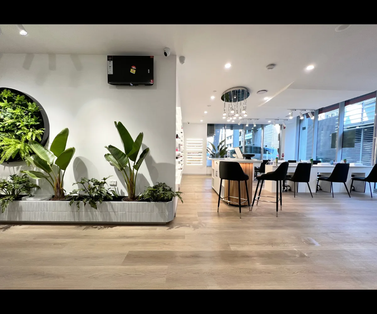 MONSTERA salon interior — birds-of-paradise planters and circular green wall, warm honey wood floors